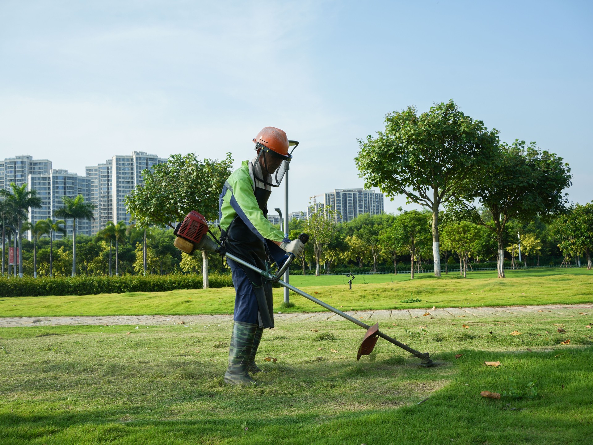 Asian workers mowing grass in the park